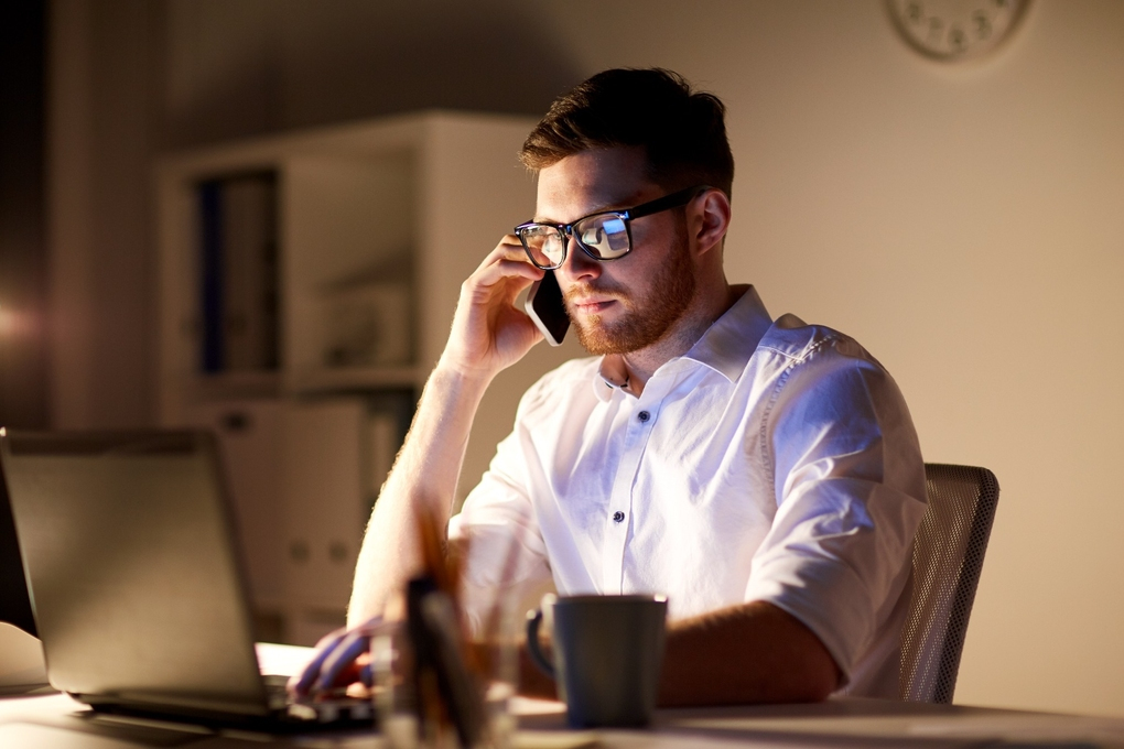 businessman-calling-on-smartphone-at-night-office-PPFL7BU
